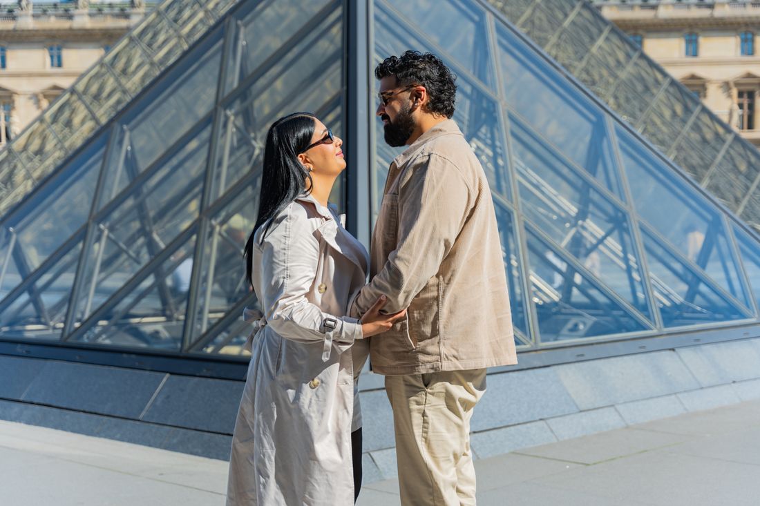 Couple enlacé devant la pyramide du Louvre à Paris