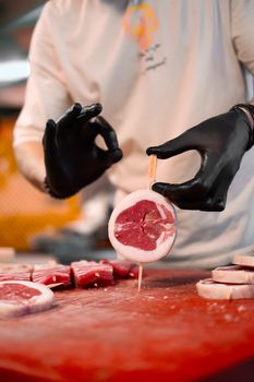 A butcher skillfully preparing fresh red meat slices with precision in a kitchen setting.