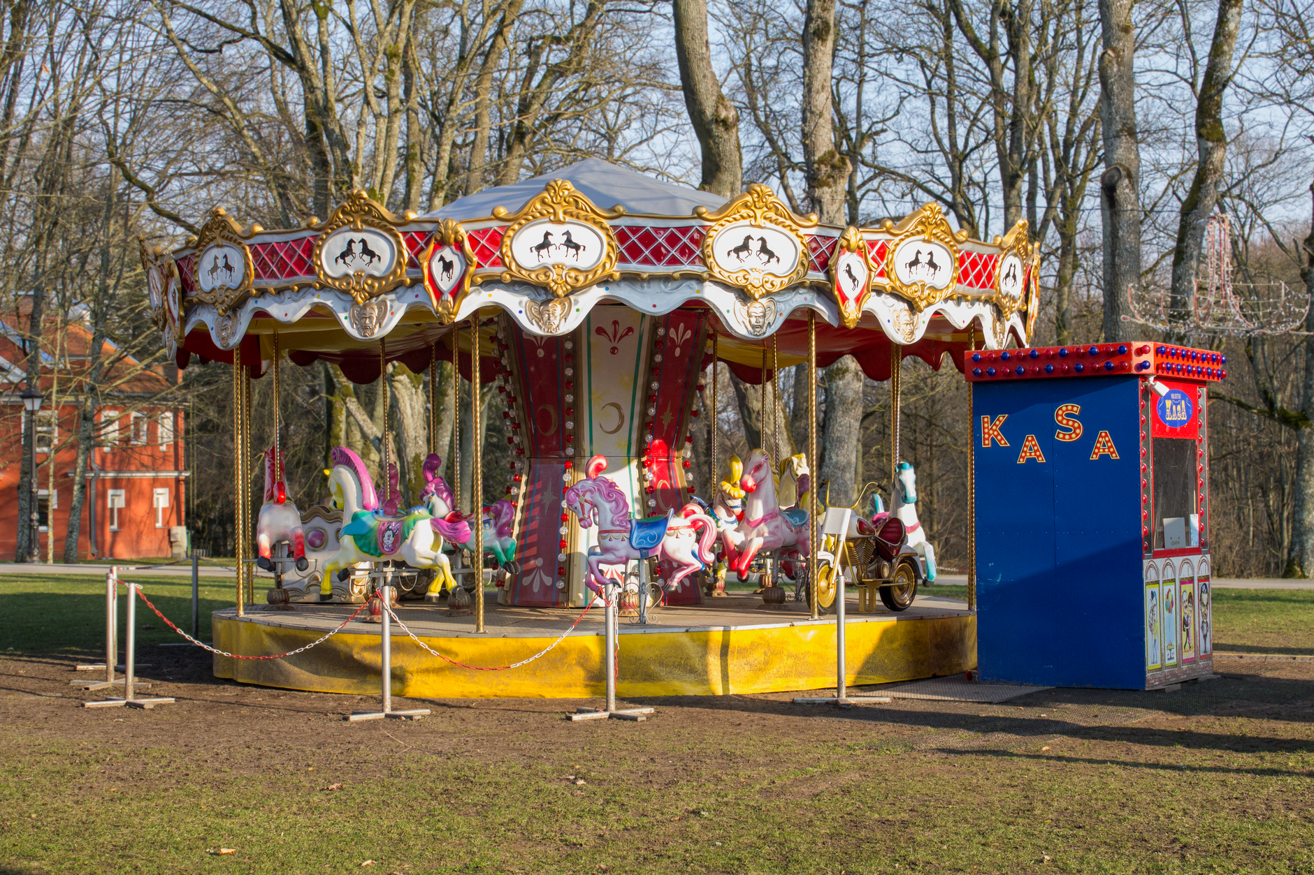 Colorful carousel in a park with ticket booth, evoking childhood nostalgia.