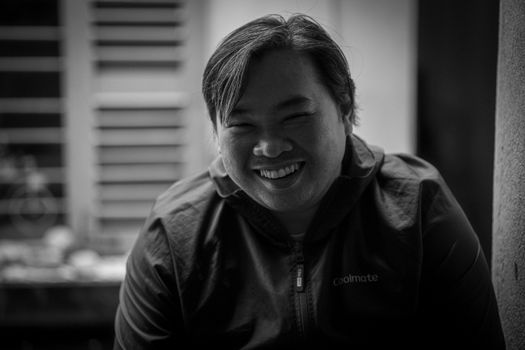 A black and white portrait of a smiling man indoors, capturing a joyful moment.