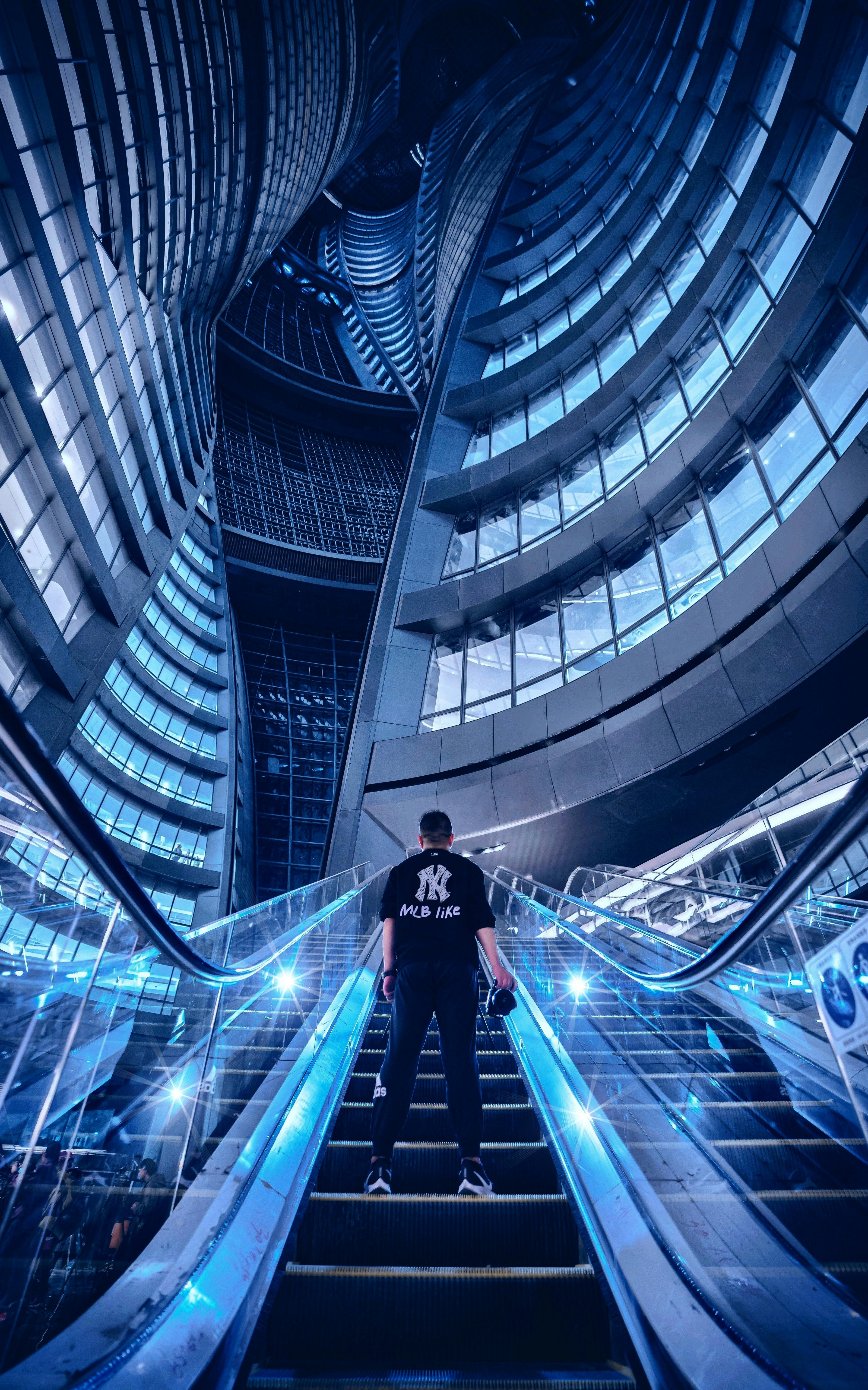 在未来派摩天大楼的自动扶梯场景中，一个人站立着，捕捉现代城市设计的精髓