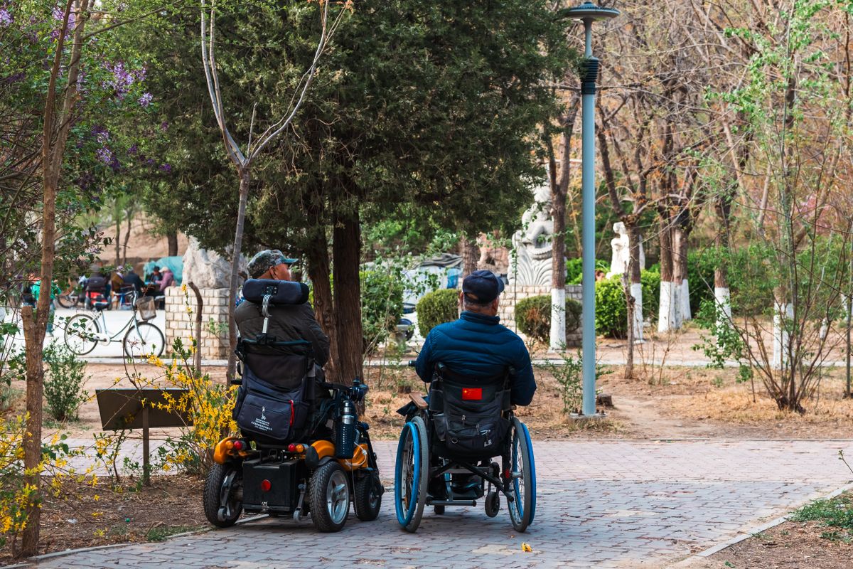 Adults in wheelchairs enjoying a calm park stroll