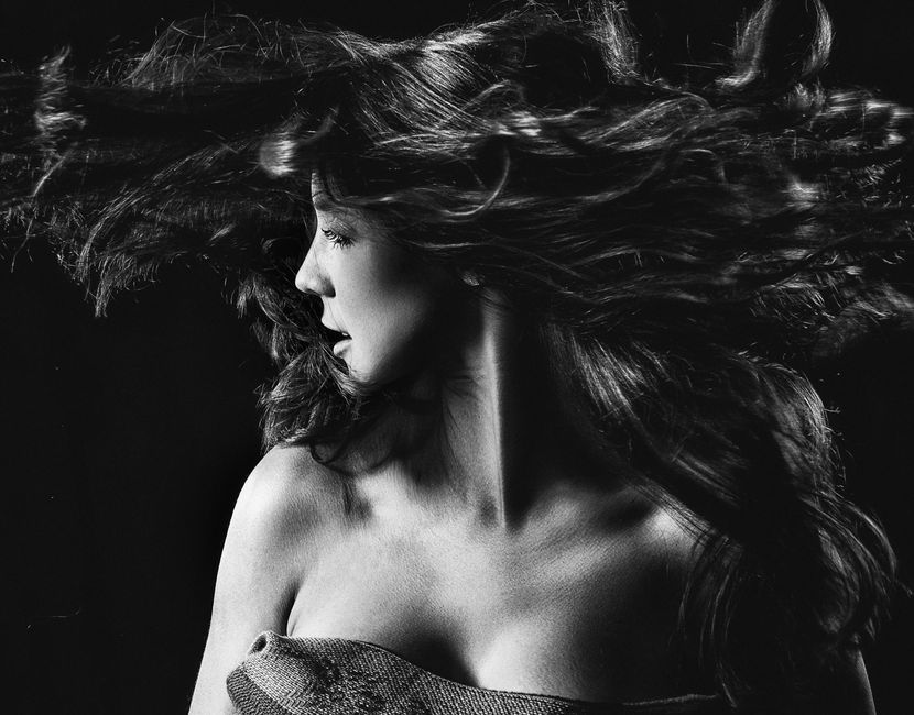 Stunning black and white portrait of a woman with flowing hair in motion, creating an artistic and dramatic look.
