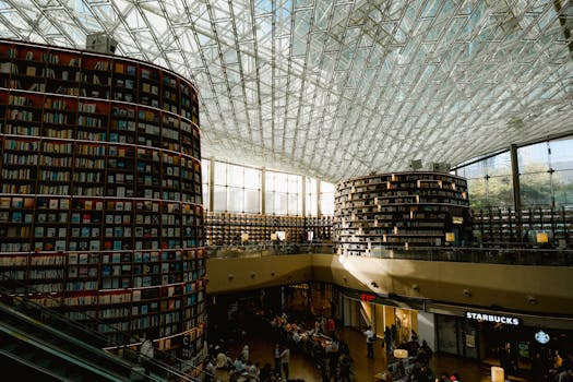 Spacious library with towering bookshelves and glass ceiling, creating a modern and open atmosphere.