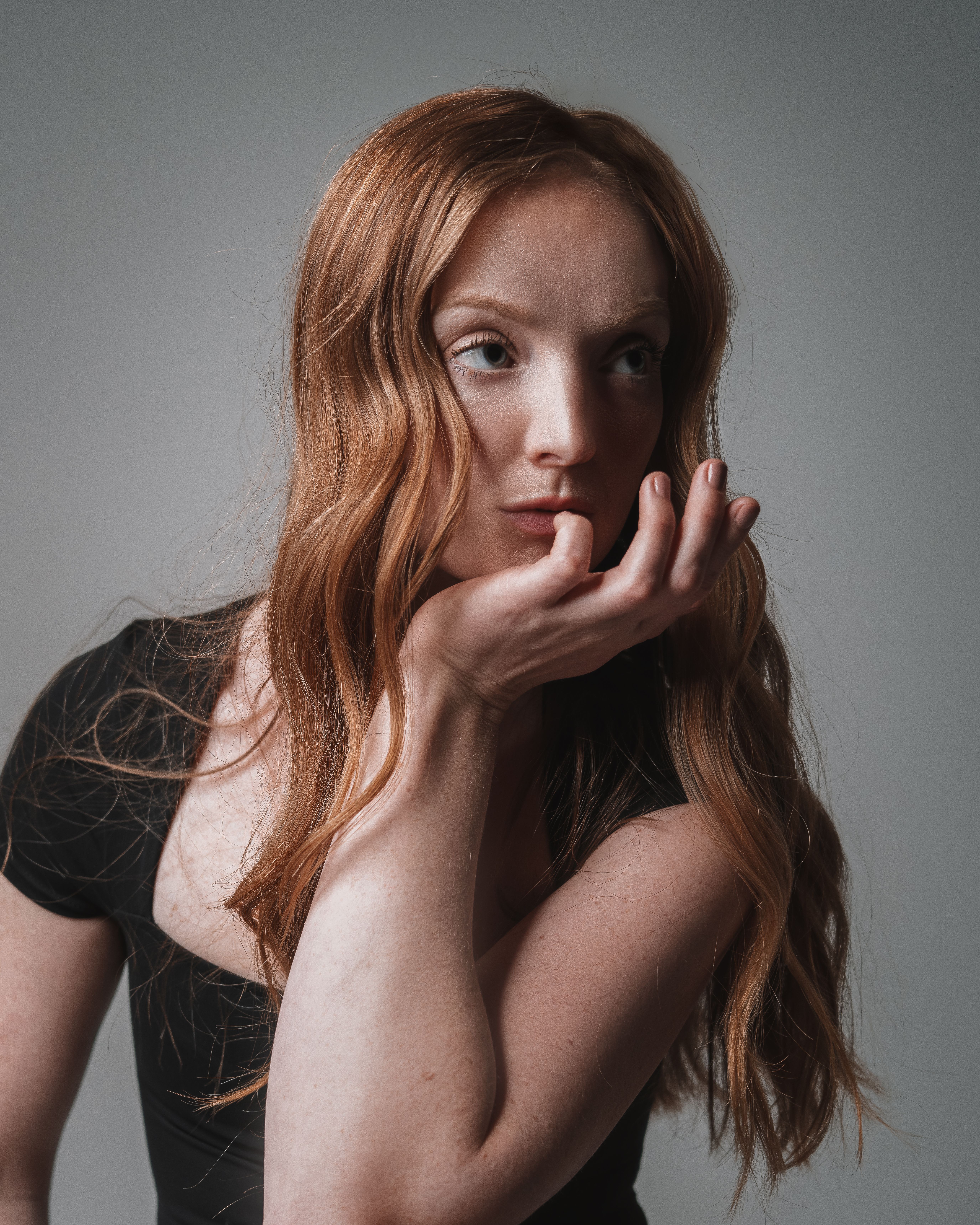 Stunning close-up portrait of a young woman with ginger hair in a contemplative pose.