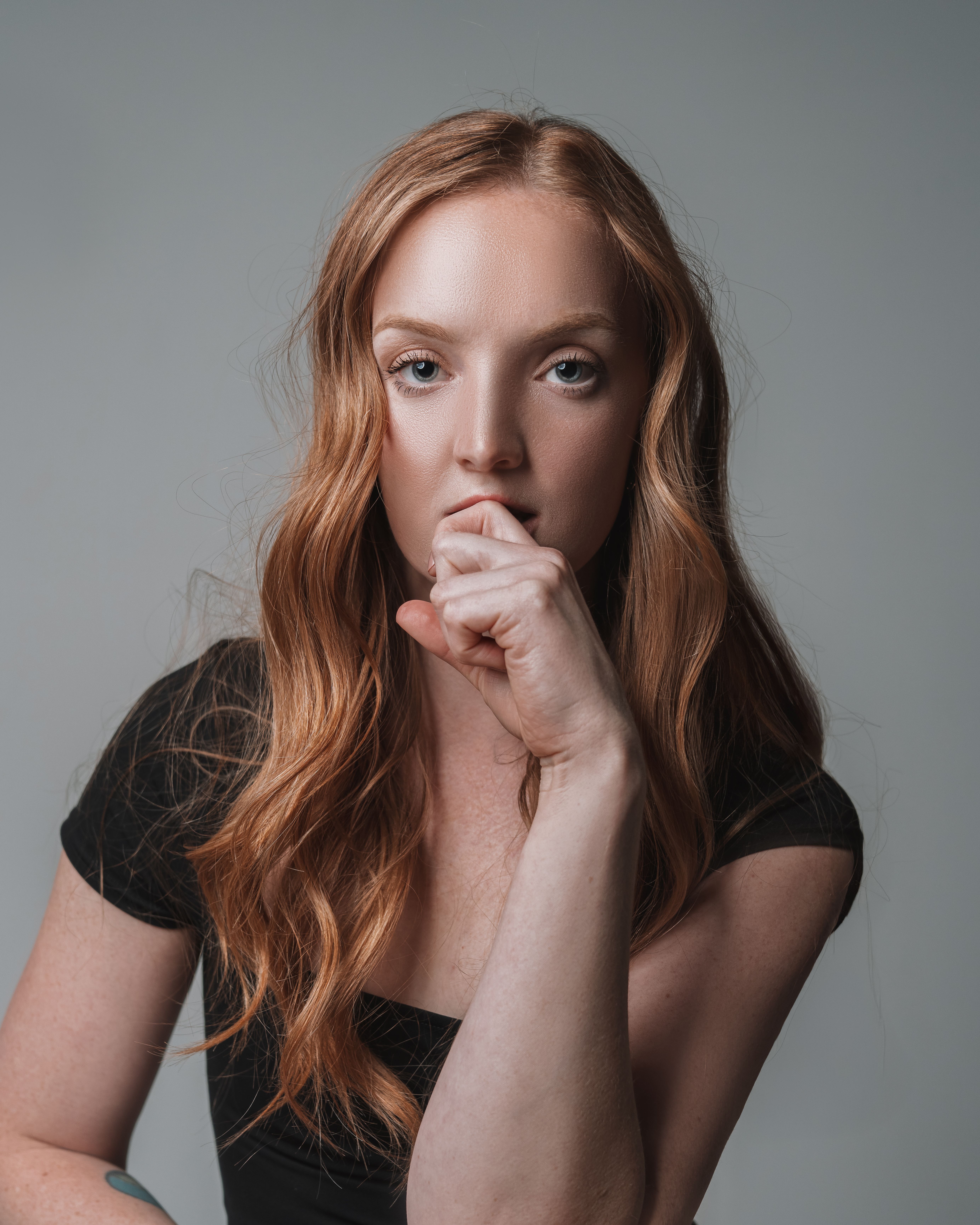 Close-up portrait of a woman with ginger hair and pensive expression, adding elegance.