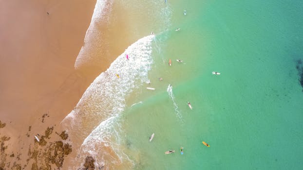 Aerial view of surfers enjoying the turquoise waves at Byron Bay beach, NSW, Australia.
