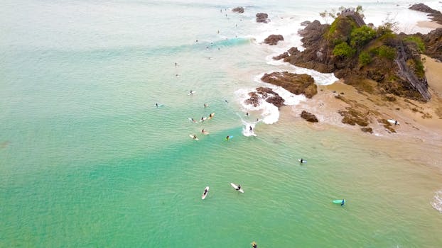 Aerial shot of surfers enjoying the waves at Byron Bay beach in New South Wales, Australia.