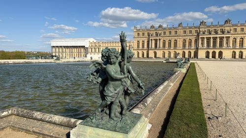Free Detailed sculpture of cherubs at Versailles Palace under a bright blue sky. Stock Photo