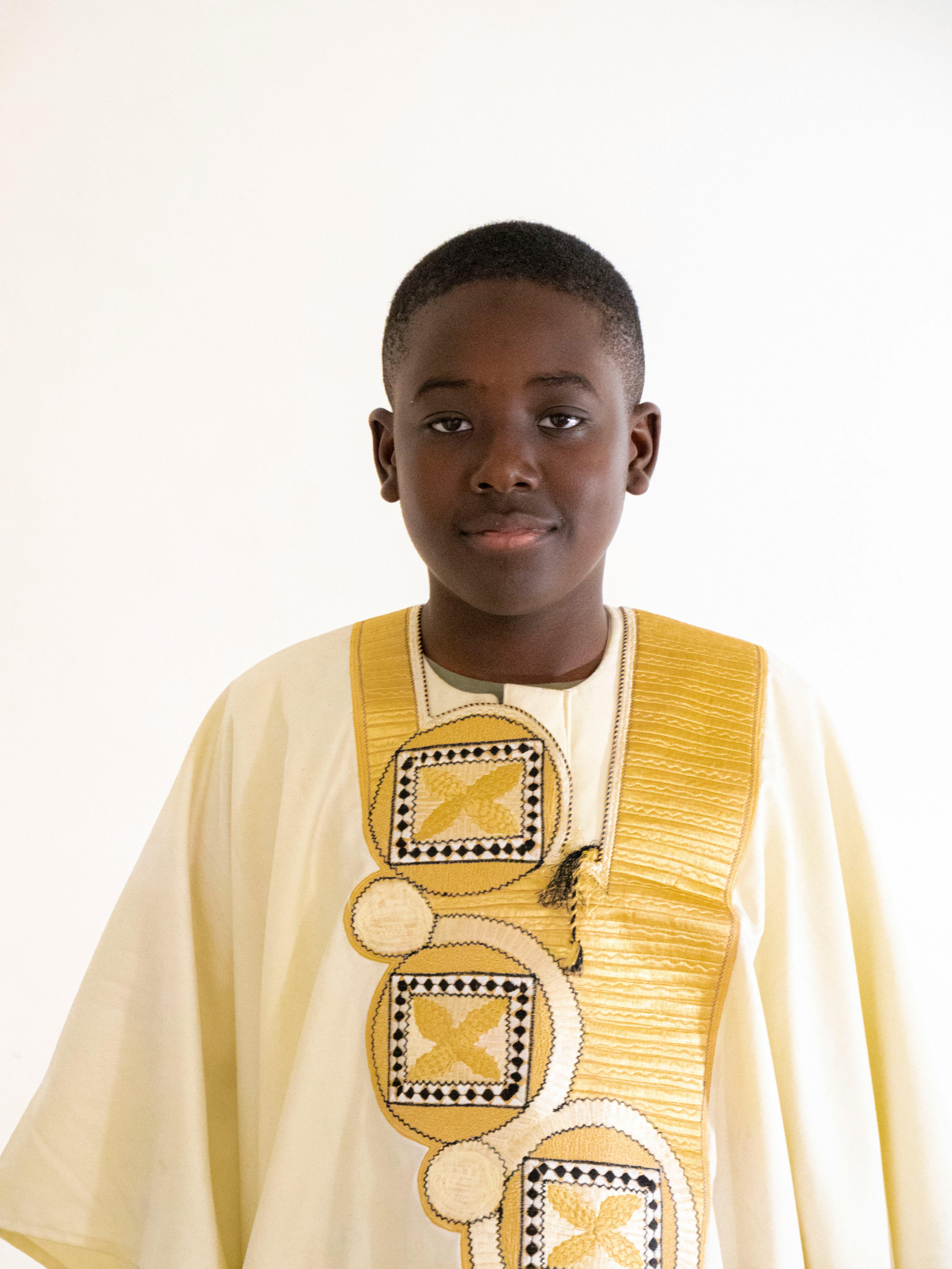 Portrait of a young boy wearing elegant traditional African clothing with a neutral background.