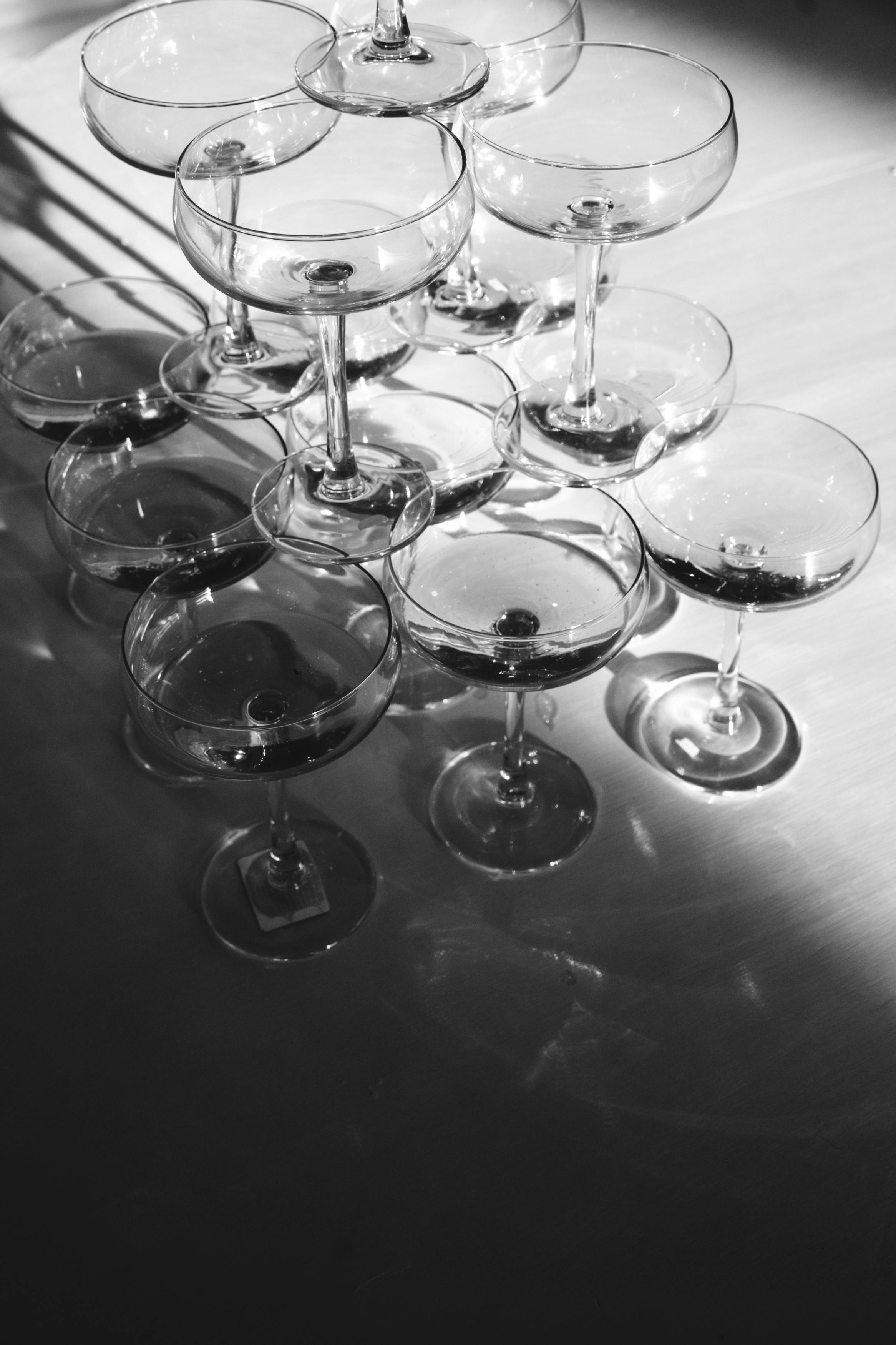 An artistic arrangement of glass champagne coupes casting shadows in black and white.