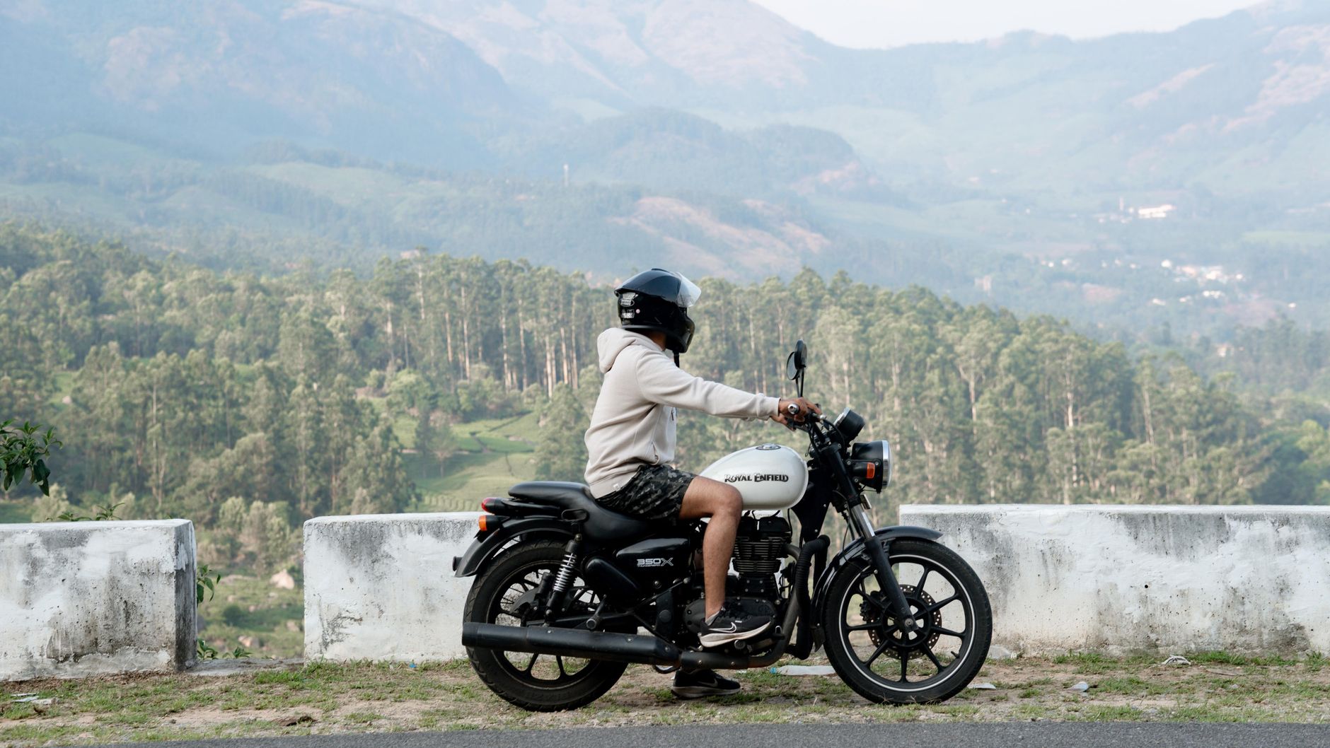 Rider on a motorcycle overlooking the lush hills of Munnar, Kerala, India.