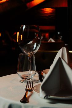 Sophisticated table setting with wine glass, napkin, and cutlery in moody lighting.