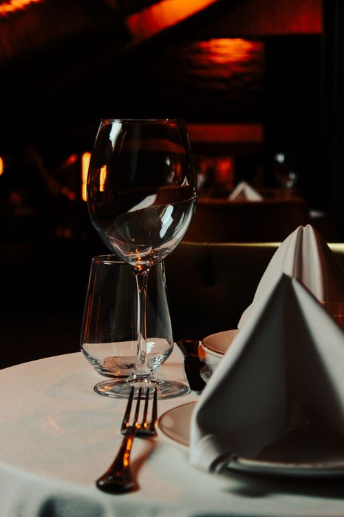 Free Sophisticated table setting with wine glass, napkin, and cutlery in moody lighting. Stock Photo