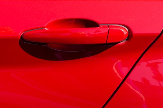 Detailed close-up image of a red car door handle with vibrant color and sleek design.