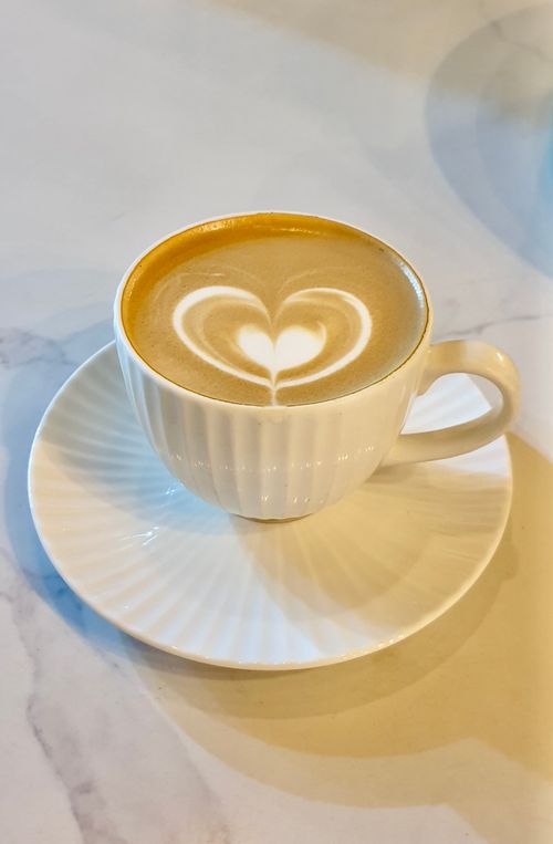 Free A cozy cup of latte with beautiful heart-shaped art, perfect for coffee lovers. Stock Photo