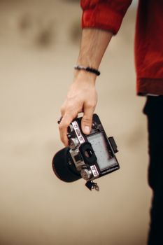 A person holding a DSLR camera outdoors, focusing on their hand and the device.