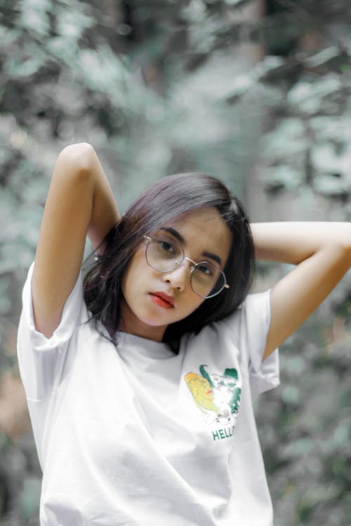 Woman in a White Crew Neck Shirt Posing with Her Hands Behind Her Head