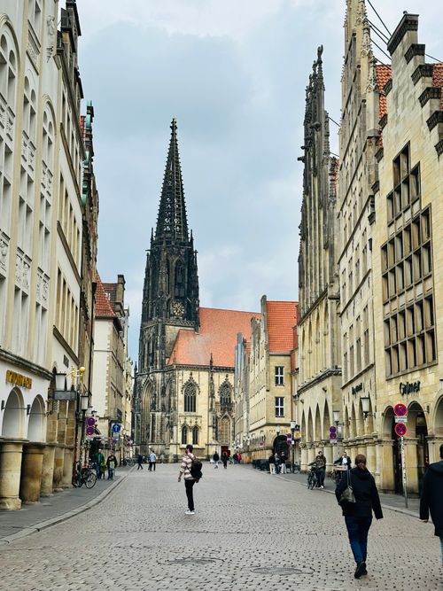 Free Street view of a Gothic cathedral in Münster with pedestrians and historic architecture. Stock Photo