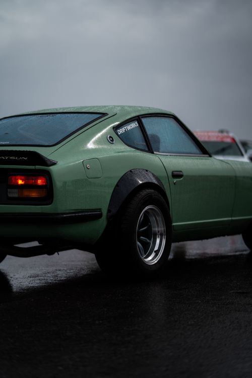 Free Vintage Datsun 240Z sports car with chrome wheels and wide tires on a rainy day. Stock Photo