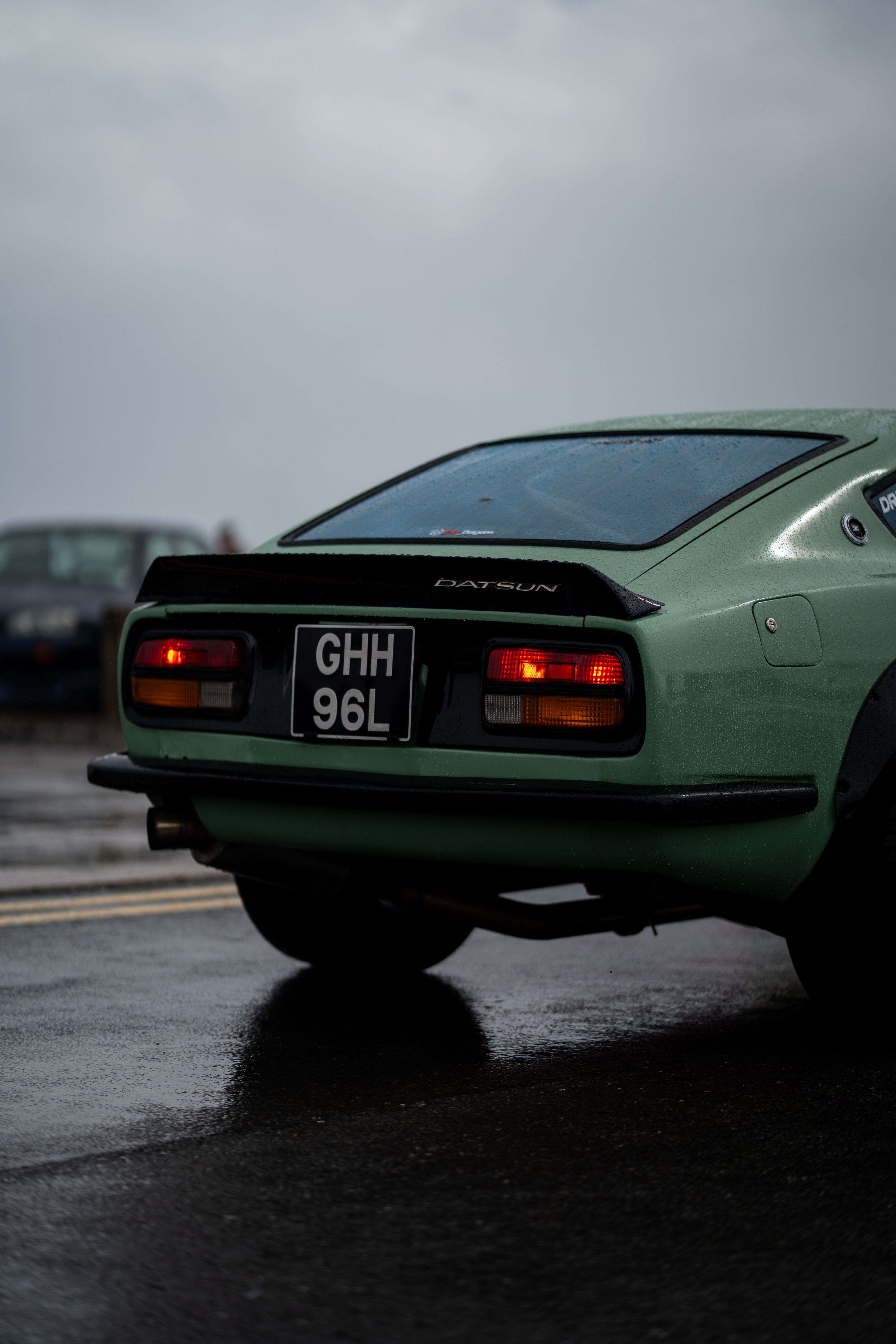 Vintage Datsun 240Z captured in the rain, showcasing retro elegance and mint green allure.
