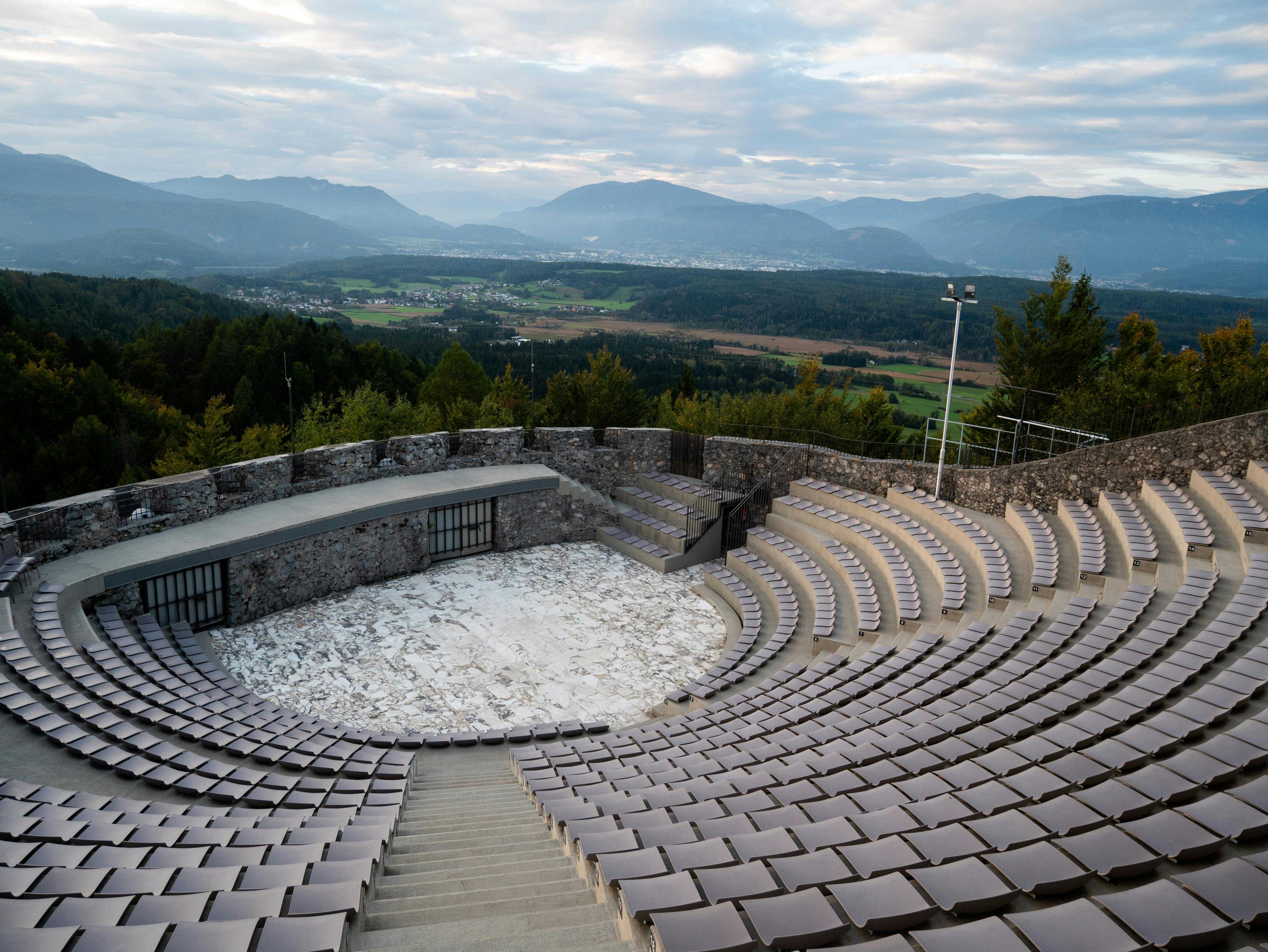 ฟรี ทัศนียภาพของโรงละครกลางแจ้งประวัติศาสตร์ในเมืองคาร์นเทน ประเทศออสเตรีย โดยมีภูเขาเป็นฉากหลัง คลังภาพถ่าย