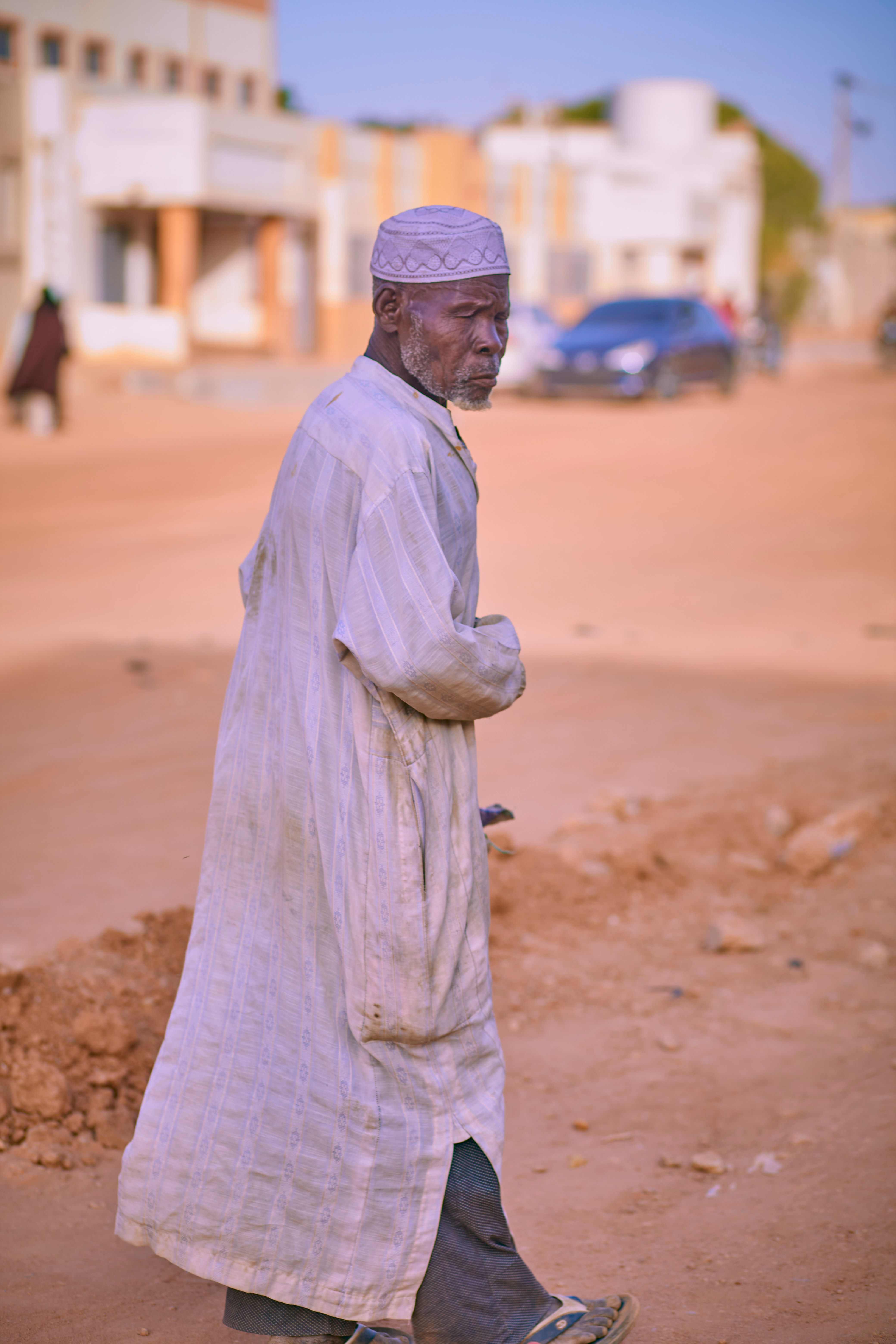 Elderly man walking through dusty urban street, Mauritania