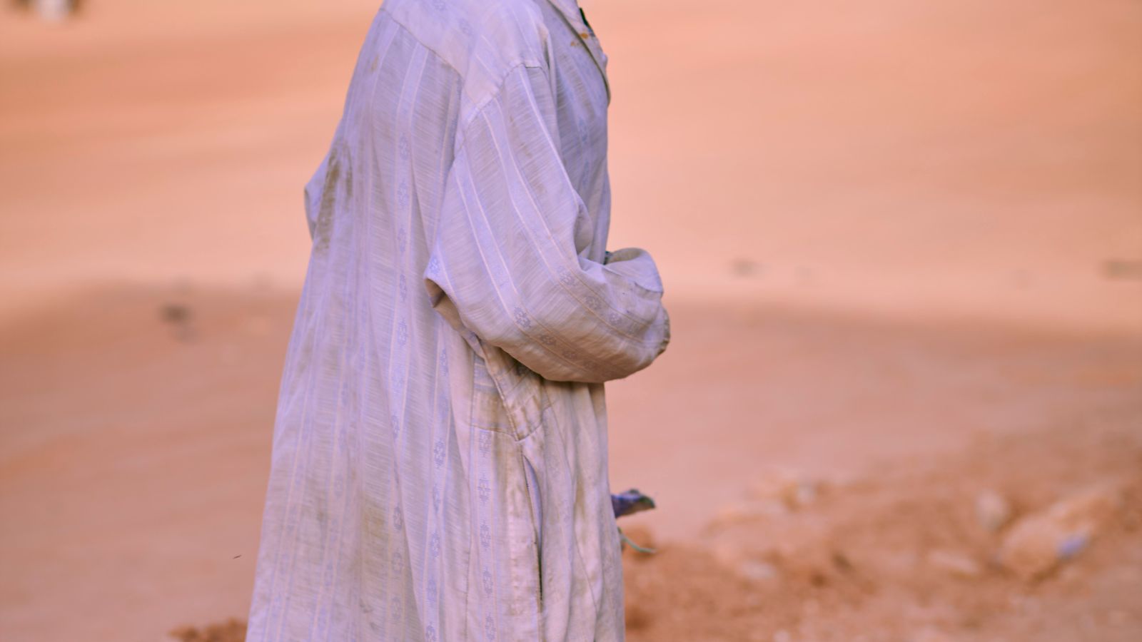 Elderly man walking through dusty urban street, Mauritania