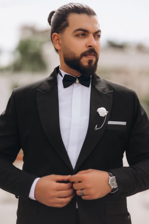 Free Stylish man with beard in formal tuxedo posing confidently outdoors. Stock Photo