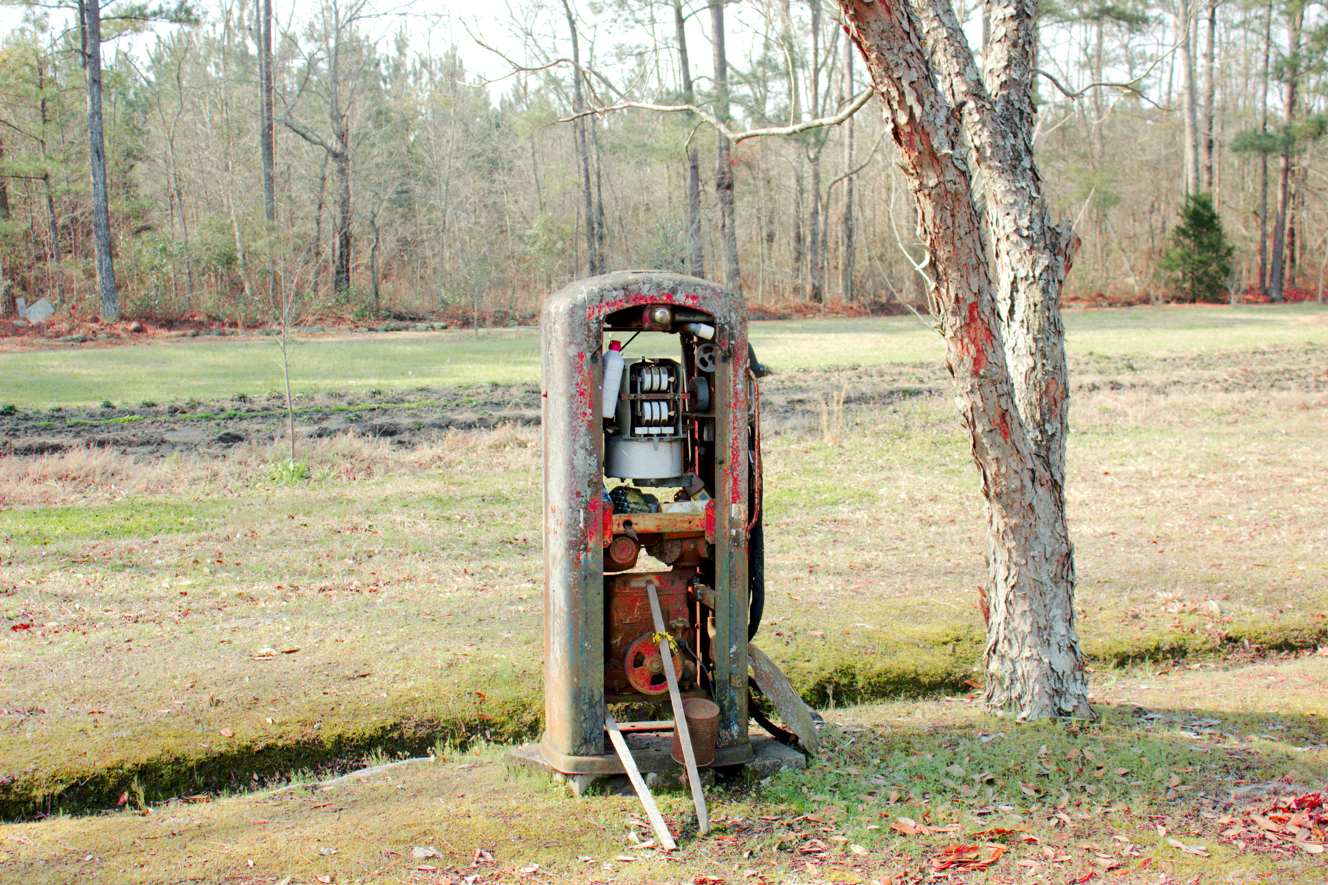 Gratuit Vieille pompe à essence rouillée abandonnée dans une clairière forestière, évoquant la nostalgie et la décadence. Photos