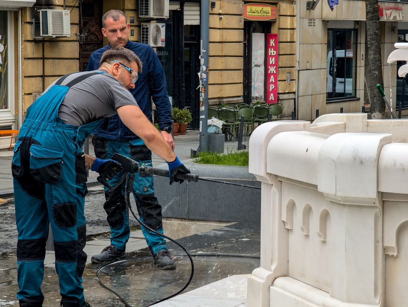 Exterior cleaning team pressure washing stonework outside a commercial property