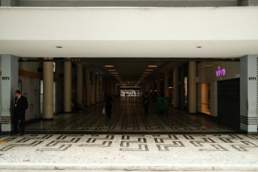 Spacious corridor in a modern shopping center with minimal lighting and people walking.
