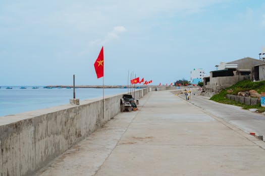 A serene view of the coastal promenade in Bình Thuận, featuring flags and azure waters.