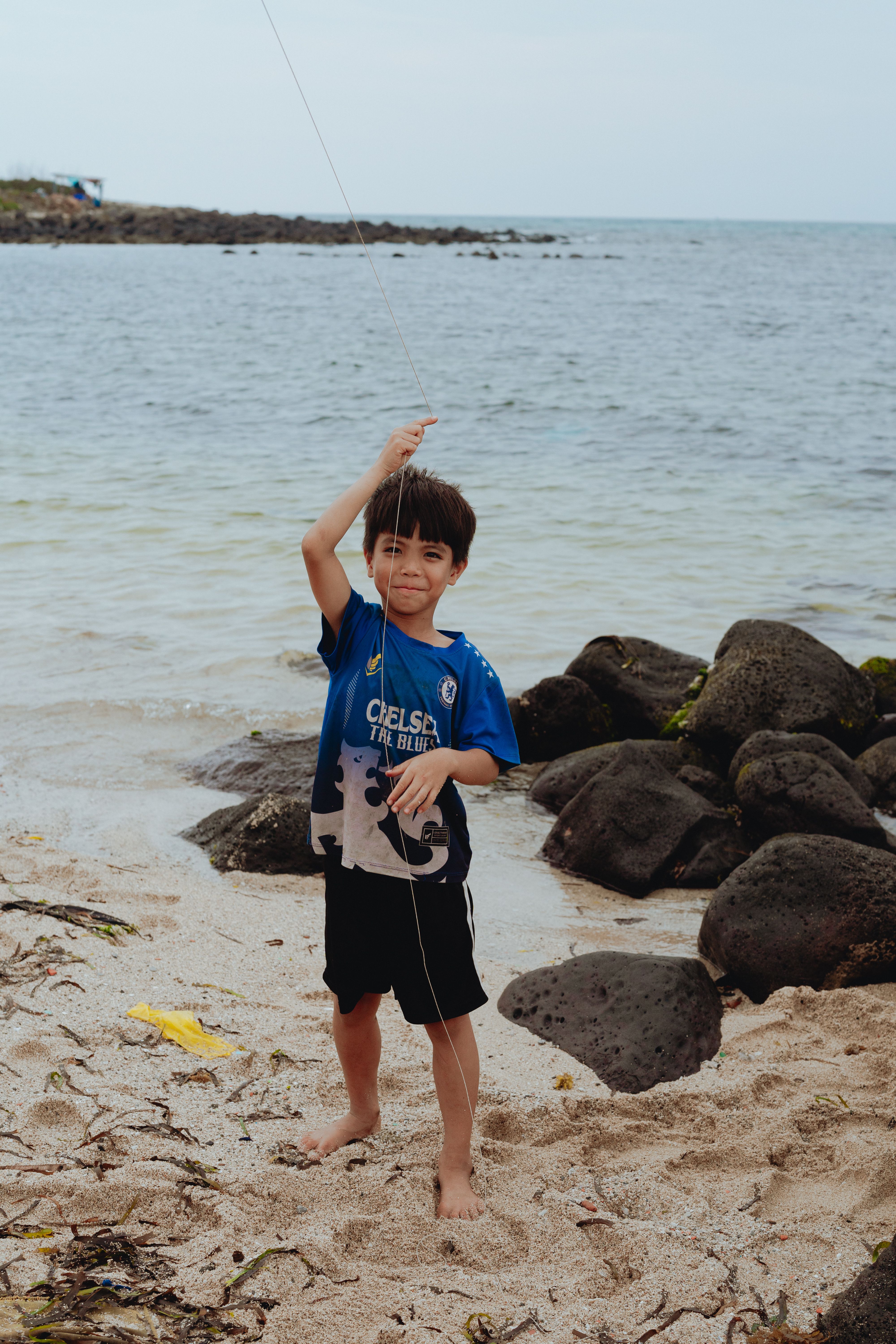 A cheerful child flying a kite on a sandy beach in Bình Thuận, Vietnam, with scenic ocean views.