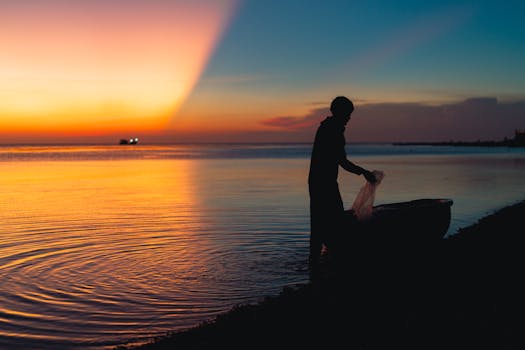 A silhouetted fisherman at work during a vibrant sunset on a beach in Bình Thuận, Vietnam.