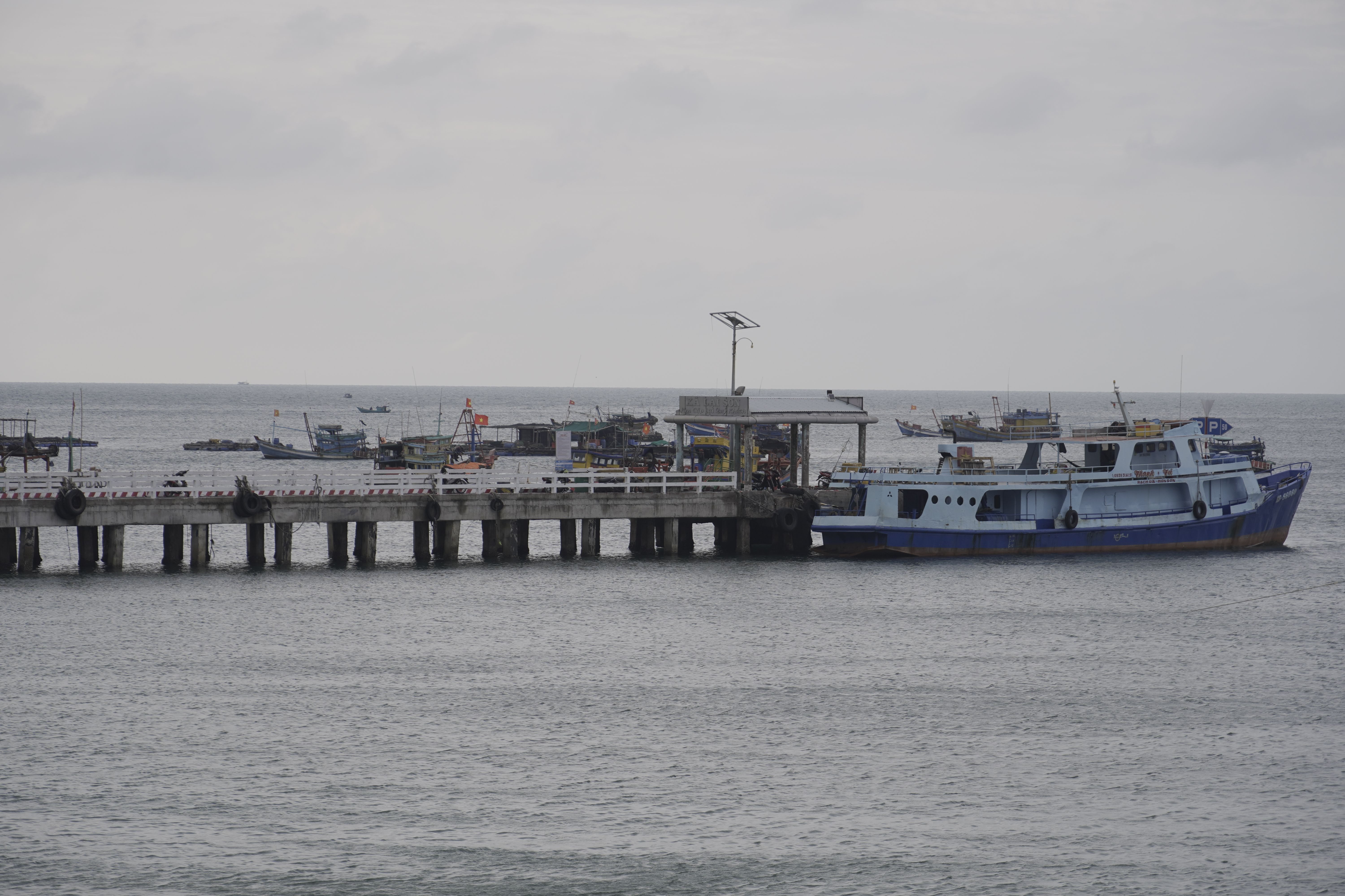 Scenic view of a dock with fishing boats on a cloudy day at sea.