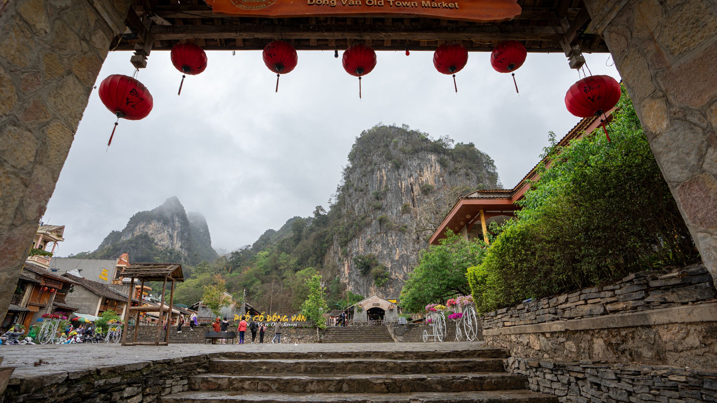 Scenic view of Dong Van Old Town Market entrance with lanterns and mountains.