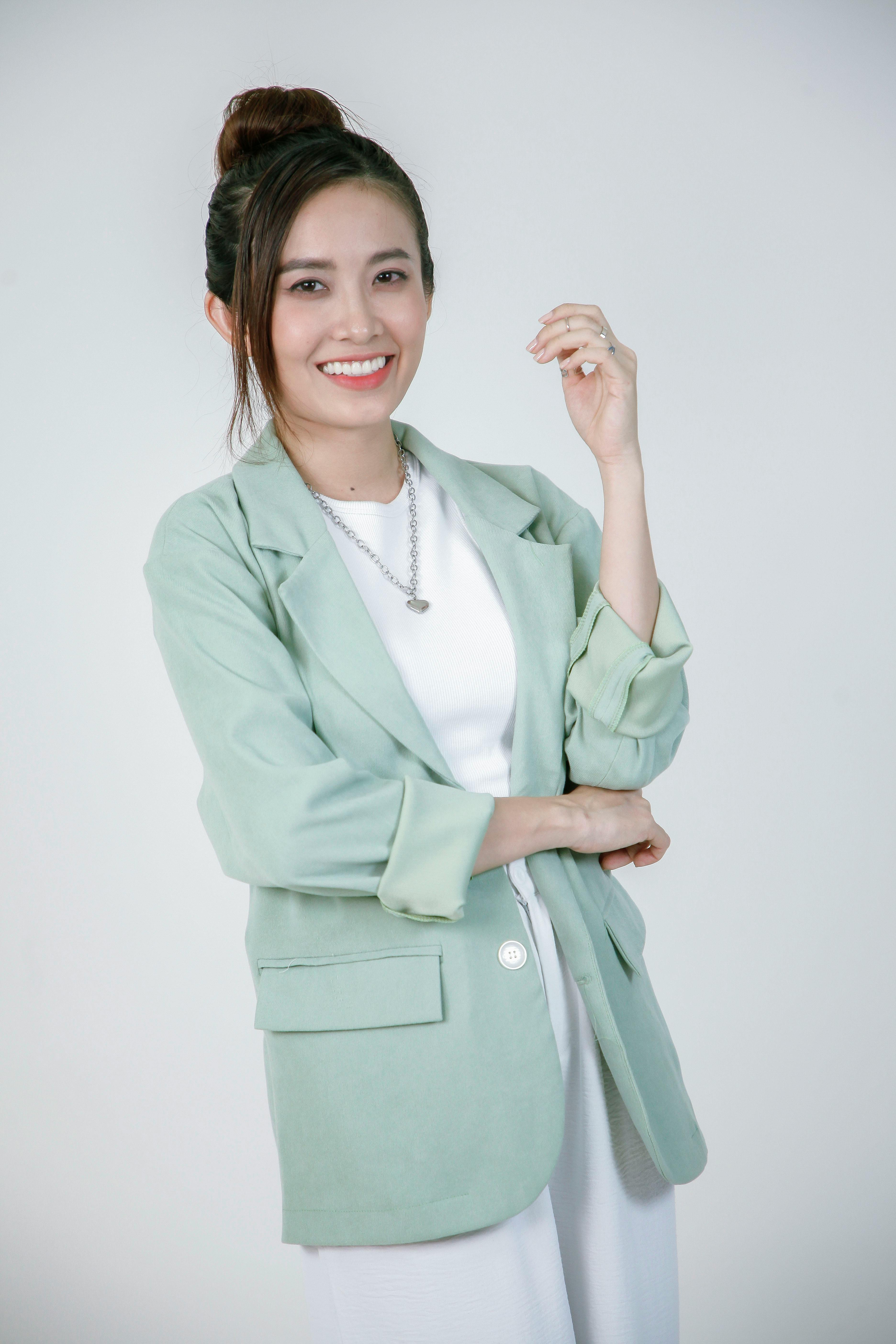 Ilmainen Muotokuva hymyilevästä naisesta, jolla on yllään tyylikäs vihreä bleiseri ja valkoinen asu. Kuvapankkikuva