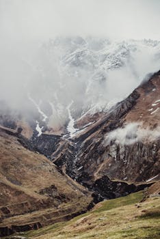 A breathtaking view of fog enveloping the rugged Kazbegi mountains, creating a serene and dramatic landscape.