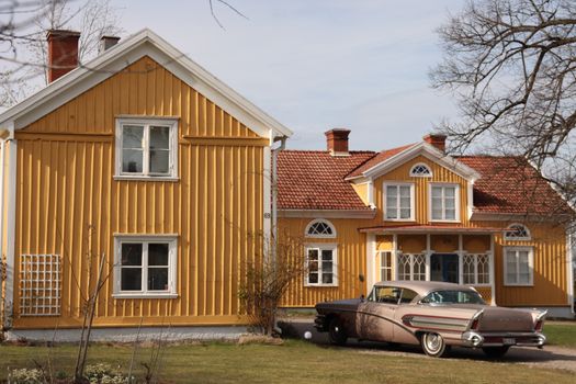 Charming yellow Swedish house with classic car parked outside in Jönköping.