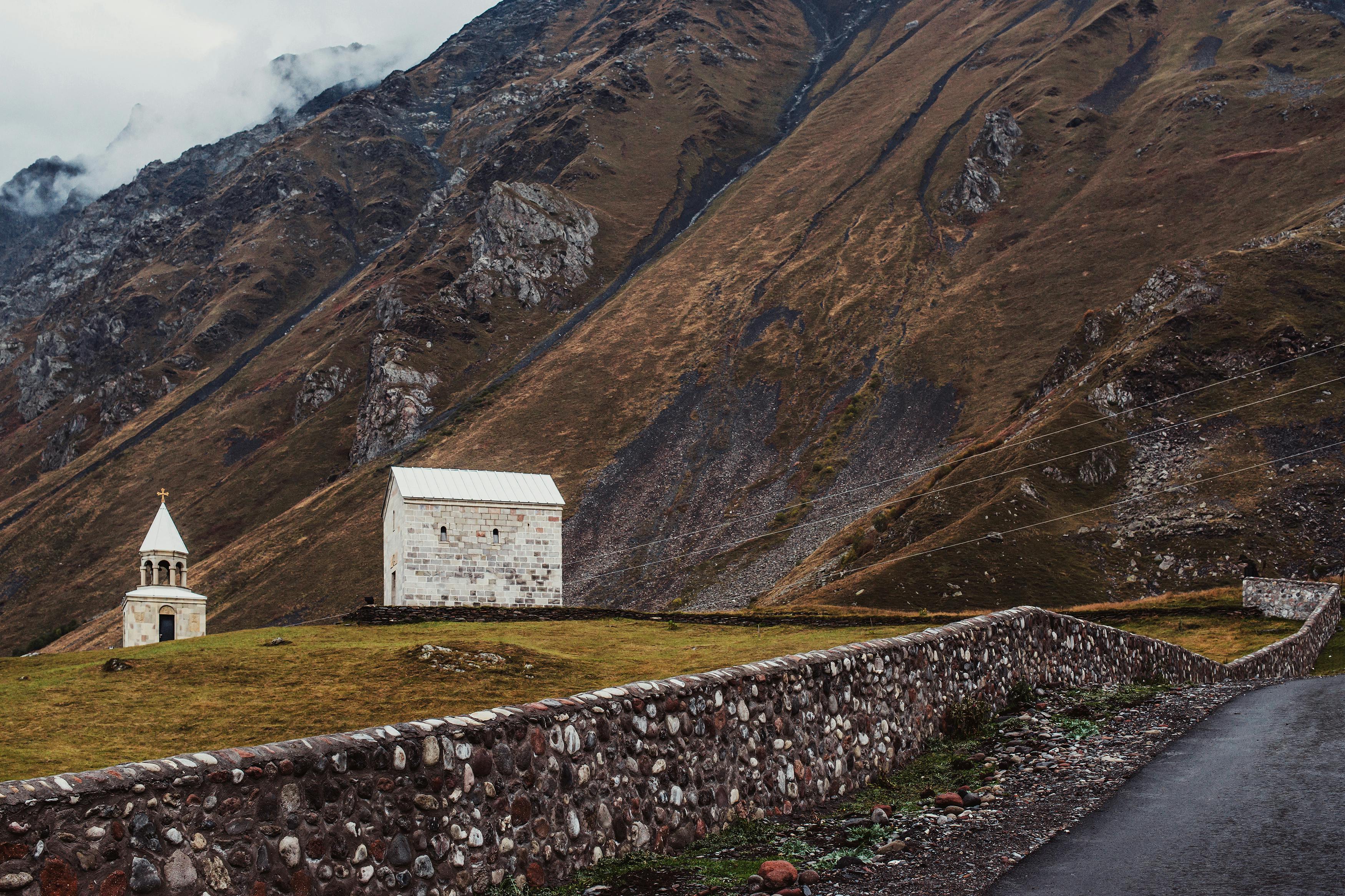 Discover the tranquil beauty of a church and mountains in Kazbegi, Georgia.