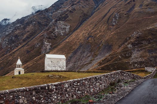 Discover the tranquil beauty of a church and mountains in Kazbegi, Georgia.