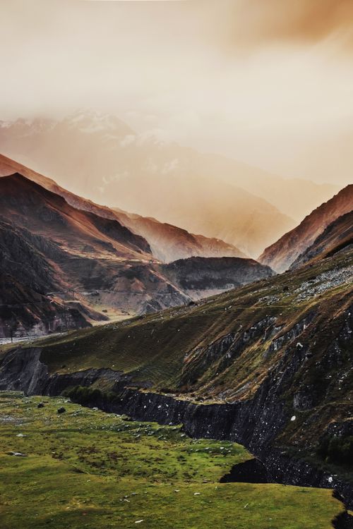Free Dramatic landscape of Mount Kazbek under a warm sunset glow, showcasing rugged mountain ranges and valleys. Stock Photo