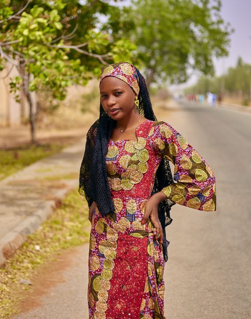 Free Confident young woman in vibrant traditional African dress standing on a sunny street. Stock Photo