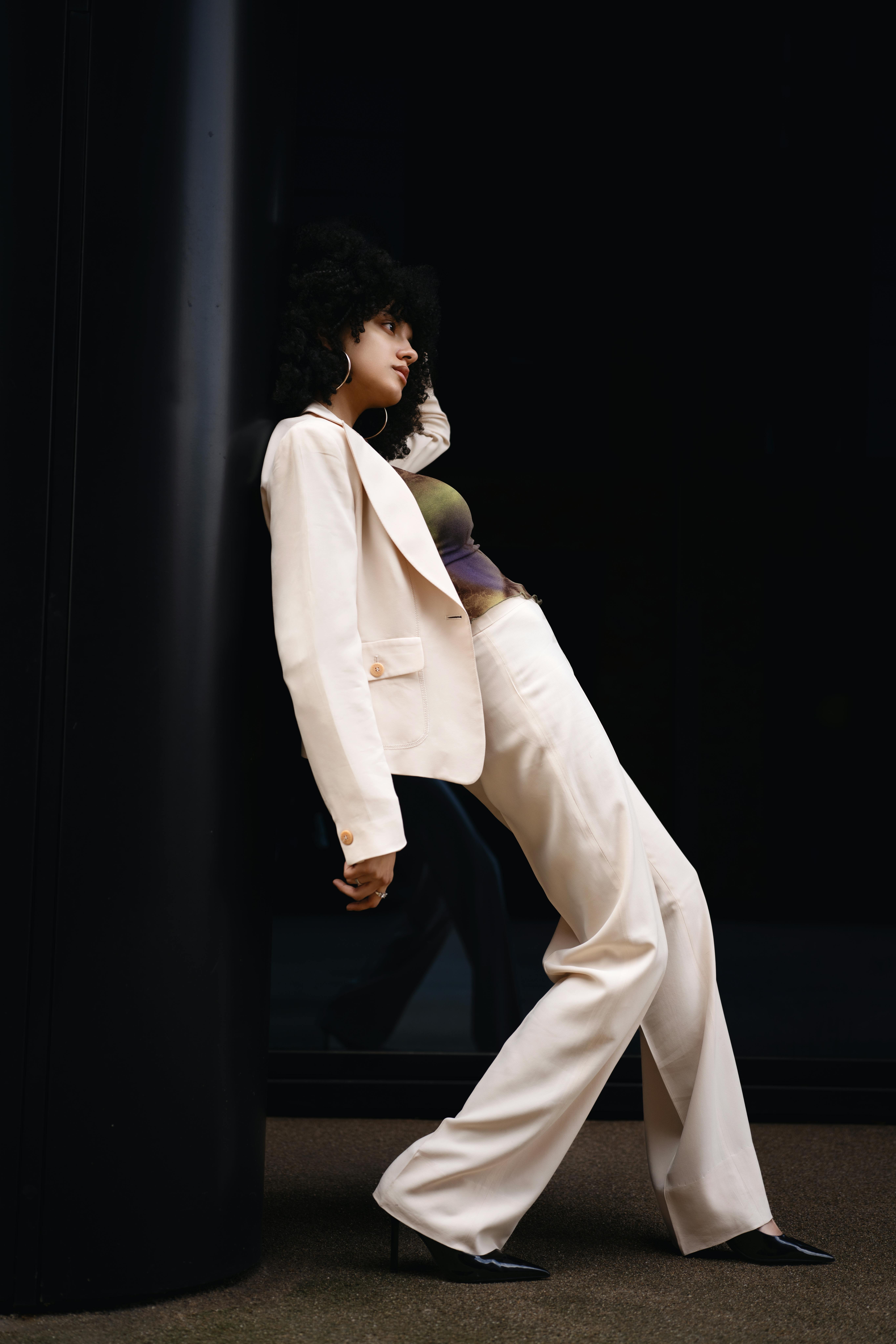 Stylish fashion model posing in a cream suit against a dark backdrop, showcasing contemporary elegance in London.