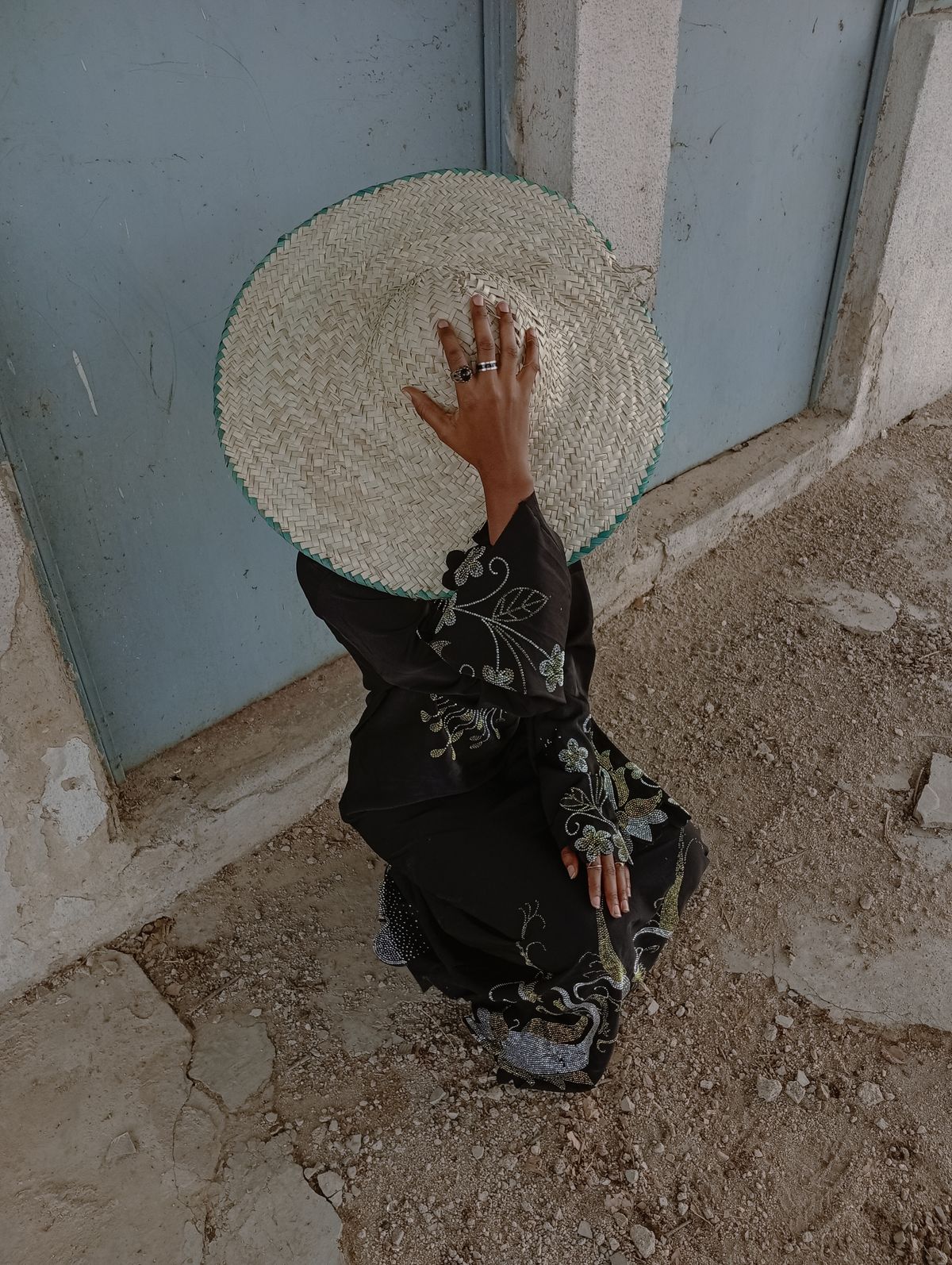 A woman in a straw hat and embroidered dress in a rustic setting, the embroidered cover-up