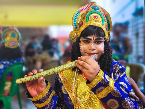 Free A young person dressed as Krishna playing a flute at an art festival in Kolkata. Stock Photo