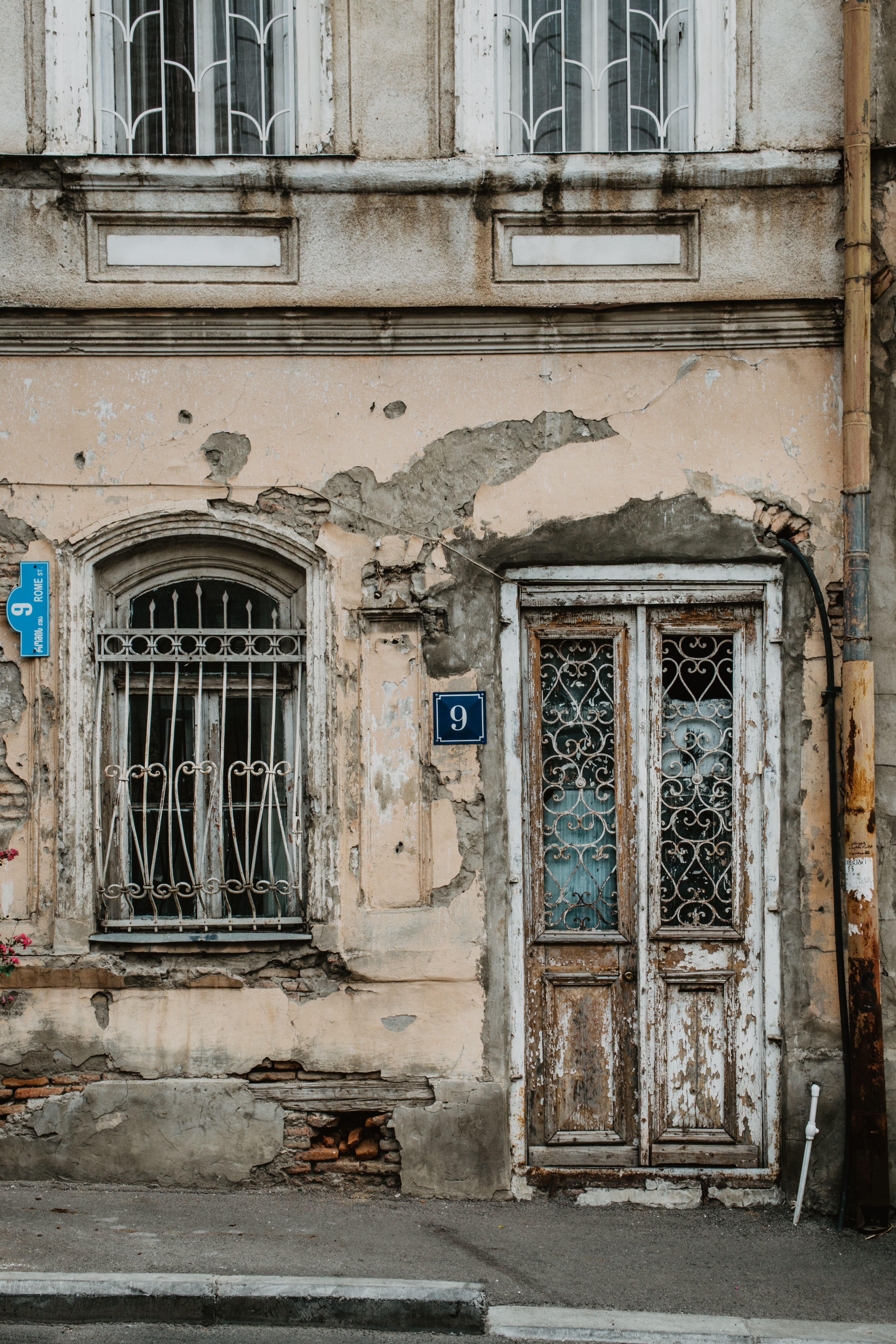 A rustic, aged facade of a building in Tbilisi with visibly worn textures and intricate metalwork.