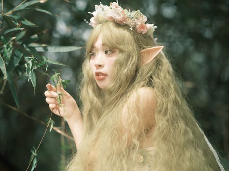 A mystical female elf with a floral crown exploring the forest, bathed in soft light.