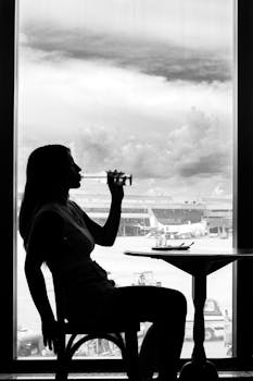 Silhouette of a woman sipping a drink at São Paulo airport with airplanes visible in the background.
